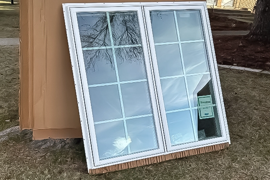 This is a photo of a brand new ProVia Window on cardboard leaning up against a tree.